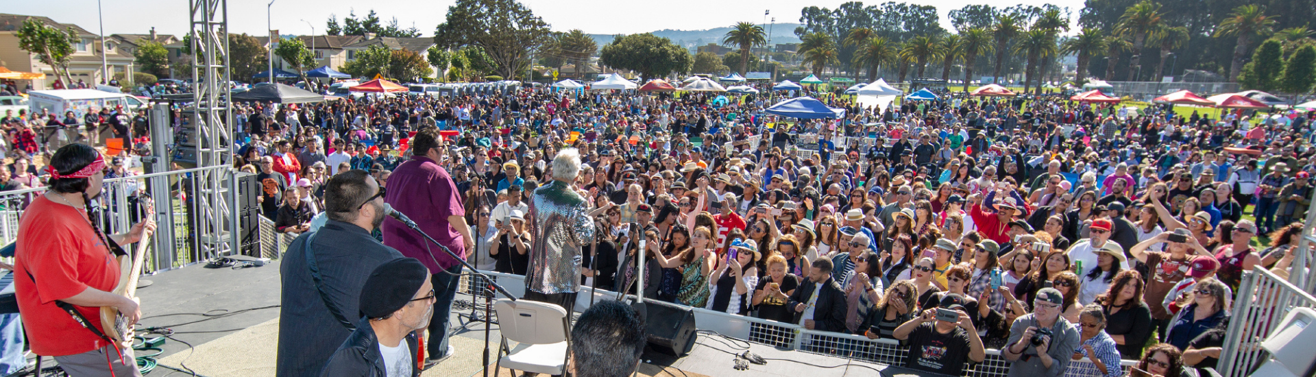 A crowd in Orange Memorial Park watching a band perform live on stage